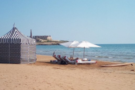 La “dura” vita da miliardario, a prender il sole sulla spiaggia di Sampieri. Mentre lo yacht resta al largo