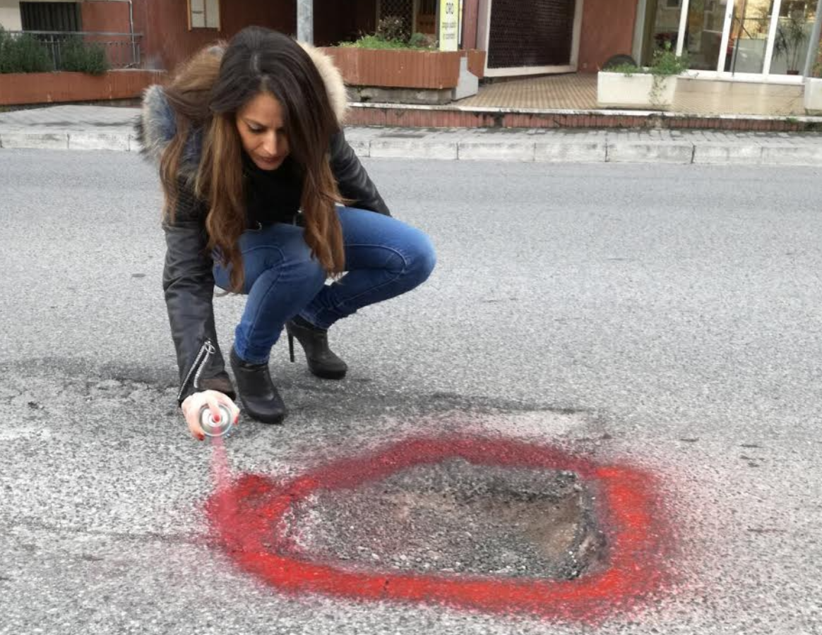 Manuela Nicita la writer, con lo spray rosso segnala le buche in strada