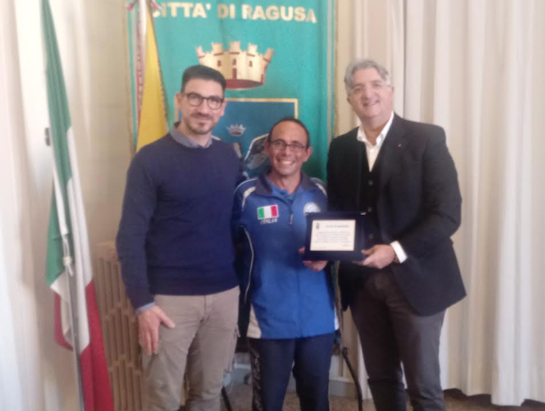 Luca Poli, componente della squadra azzurra di pesca con canna da riva, riceve una targa ricordo dal Comune