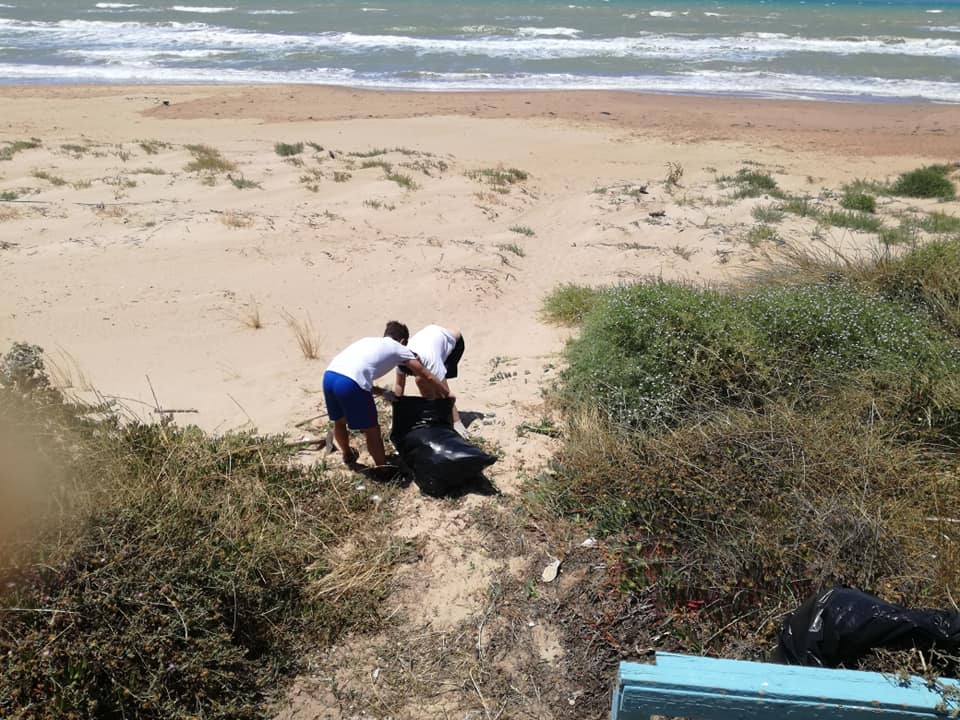 In silenzio e senza clamore, alcuni giovani puliscono le scale di accesso alla spiaggia di Scoglitti